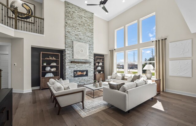 living room with a towering ceiling, a stone fireplace, and dark hardwood / wood-style floors