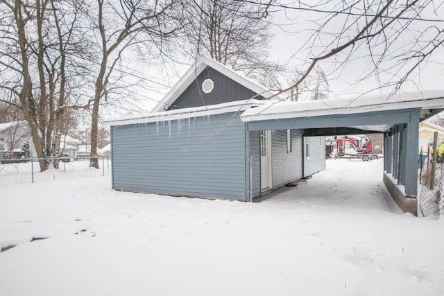 snow covered garage featuring a carport