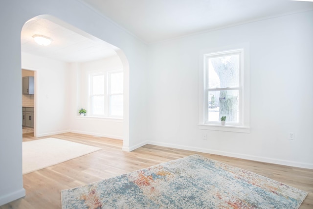 unfurnished room featuring light hardwood / wood-style flooring, crown molding, and a healthy amount of sunlight