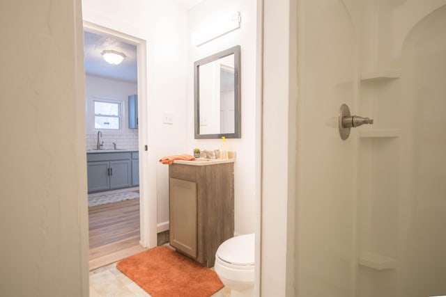 bathroom featuring toilet, vanity, backsplash, and walk in shower