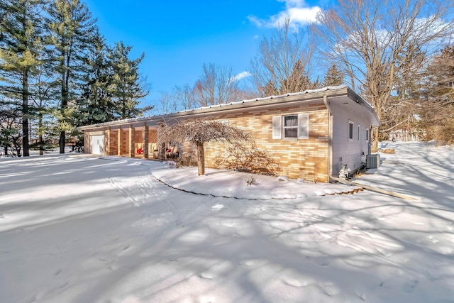 view of snow covered exterior with a garage and cooling unit