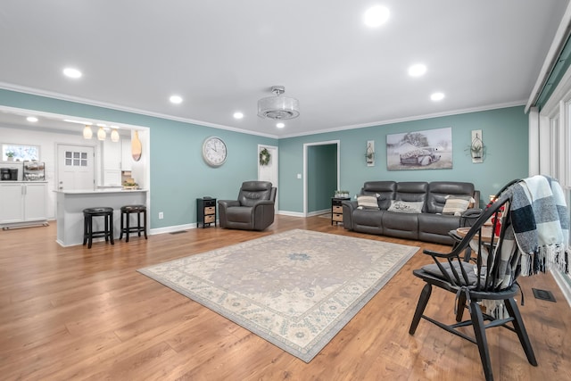 living room with ornamental molding and light hardwood / wood-style floors