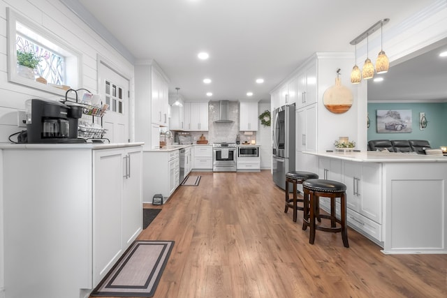 kitchen featuring hanging light fixtures, white cabinets, kitchen peninsula, and appliances with stainless steel finishes