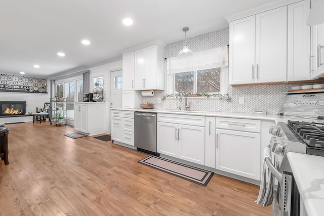 kitchen with appliances with stainless steel finishes, a fireplace, white cabinets, and hanging light fixtures