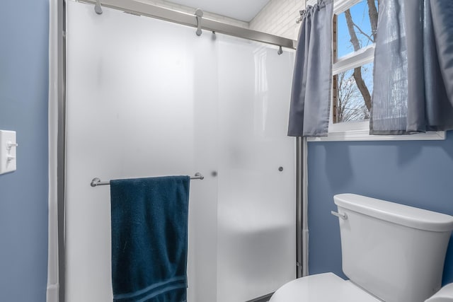 bathroom featuring toilet and an enclosed shower