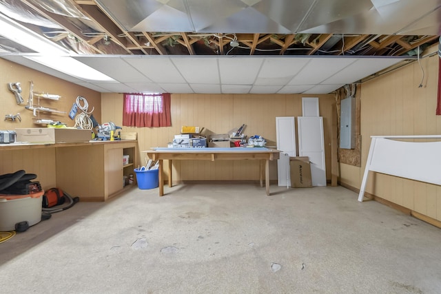 basement with a paneled ceiling and electric panel