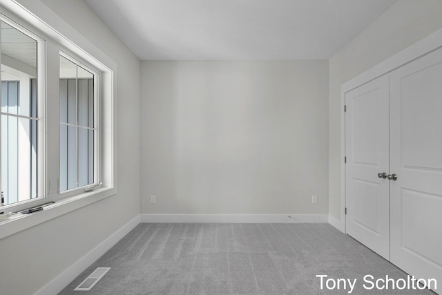 unfurnished bedroom with visible vents, carpet, baseboards, and a closet