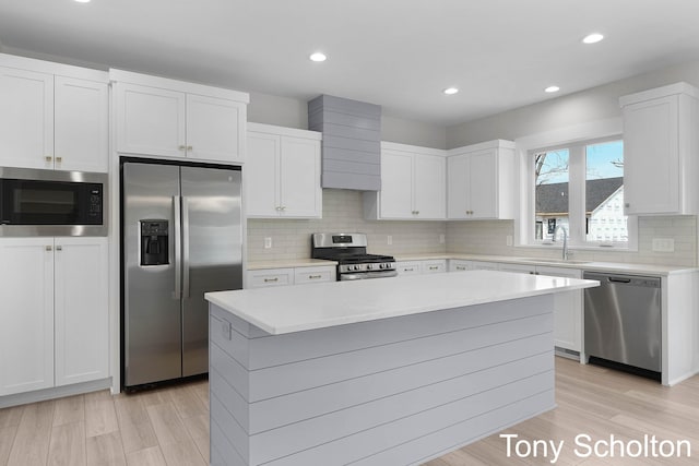 kitchen with light countertops, stainless steel appliances, a sink, and light wood finished floors