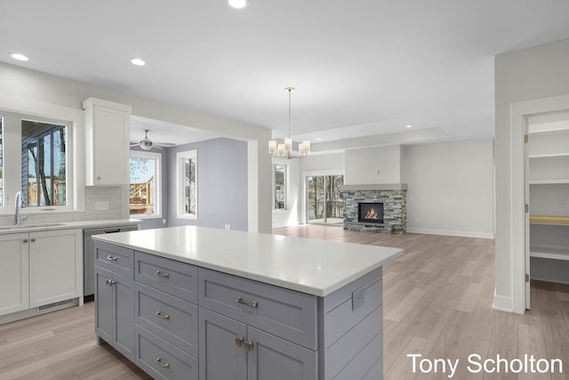 kitchen with stainless steel dishwasher, a sink, a wealth of natural light, and light countertops