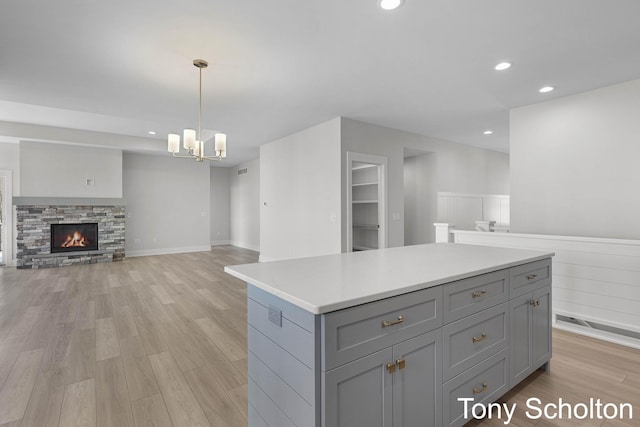 kitchen with gray cabinets, light countertops, a notable chandelier, light wood-style floors, and open floor plan