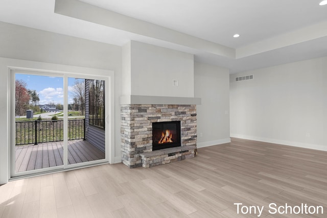 unfurnished living room with baseboards, visible vents, wood finished floors, and a fireplace