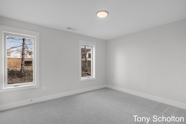 unfurnished room featuring a wealth of natural light, carpet, and visible vents