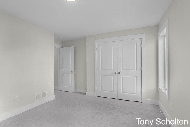 unfurnished bedroom featuring visible vents, baseboards, carpet floors, and a closet
