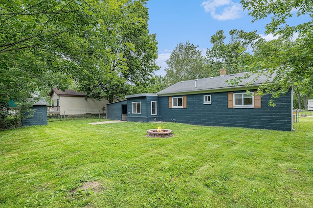 rear view of house with a lawn and a fire pit