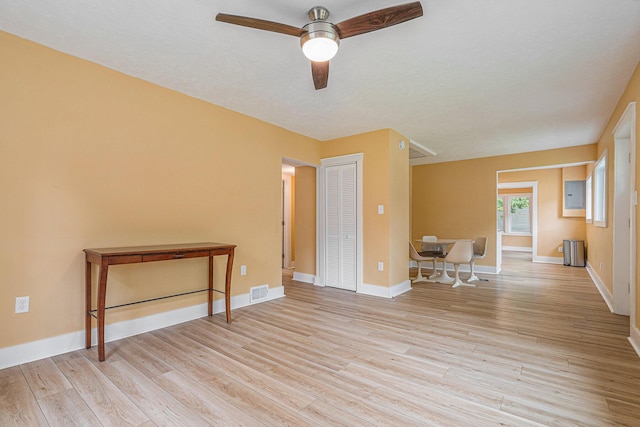 spare room with ceiling fan, electric panel, and light wood-type flooring