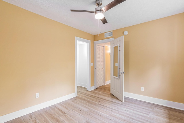 empty room with ceiling fan, a textured ceiling, and light hardwood / wood-style flooring