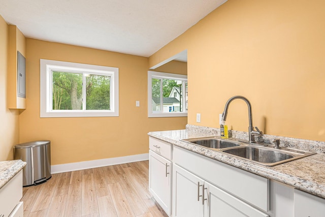 kitchen with light stone countertops, sink, and white cabinets