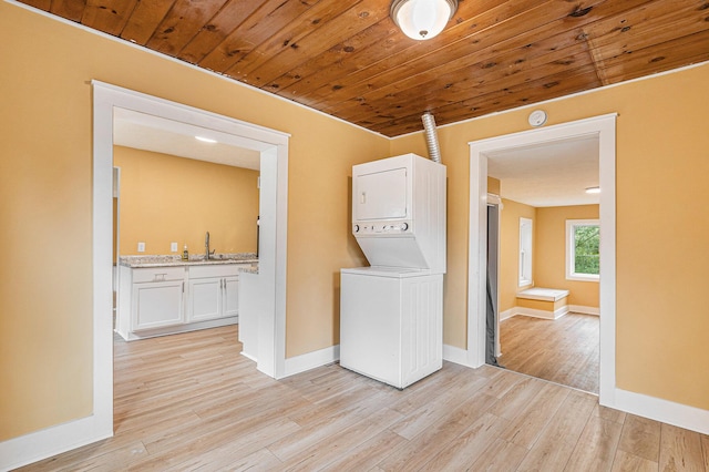 laundry room featuring light hardwood / wood-style floors, wooden ceiling, sink, and stacked washing maching and dryer