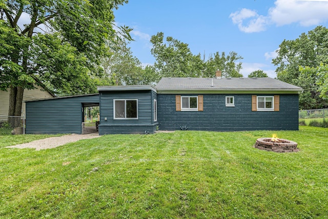 rear view of property with a lawn and a fire pit