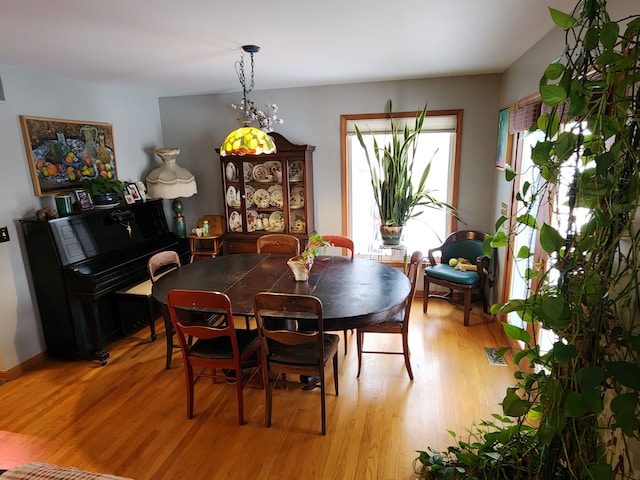 dining area with light wood-type flooring and an inviting chandelier