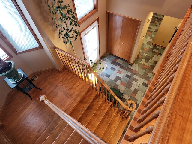 staircase with wood-type flooring and a high ceiling