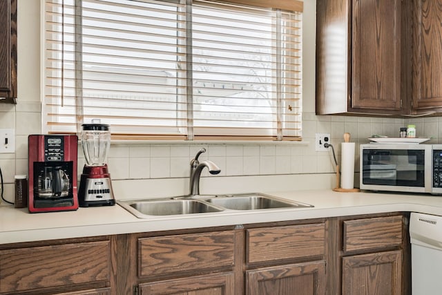 kitchen featuring white dishwasher, backsplash, and sink