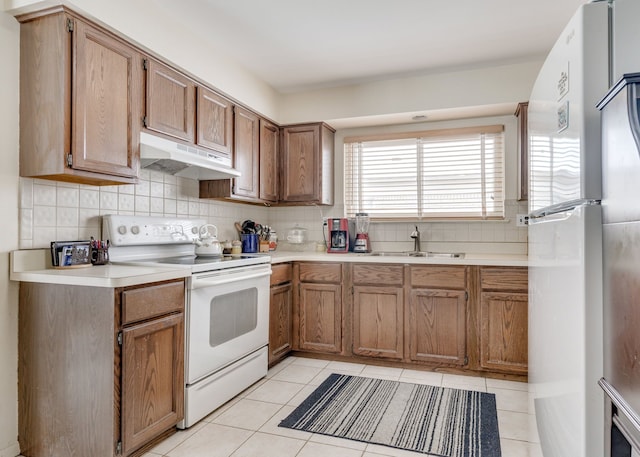 kitchen featuring light tile patterned floors, tasteful backsplash, fridge, electric stove, and sink