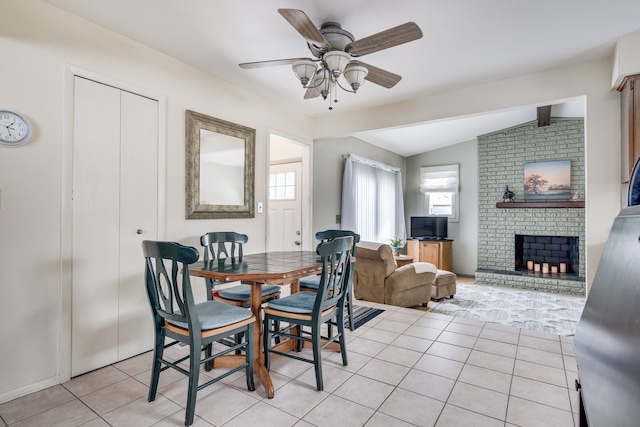 tiled dining room featuring ceiling fan, vaulted ceiling with beams, and a fireplace