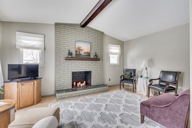 living room with vaulted ceiling with beams, a brick fireplace, and light hardwood / wood-style floors