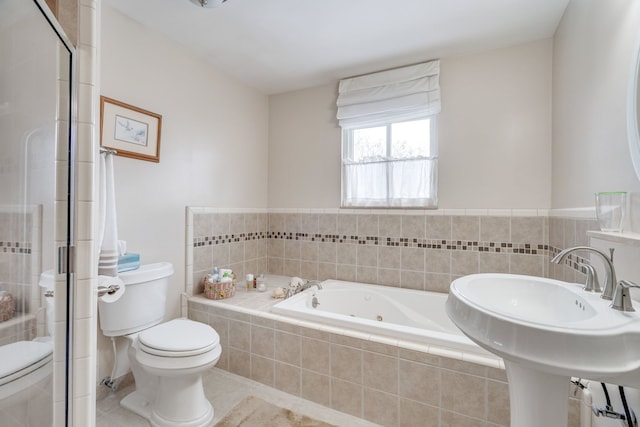 bathroom featuring toilet, tiled bath, and sink