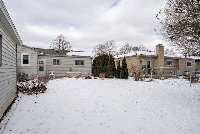 snow covered house with a wooden deck