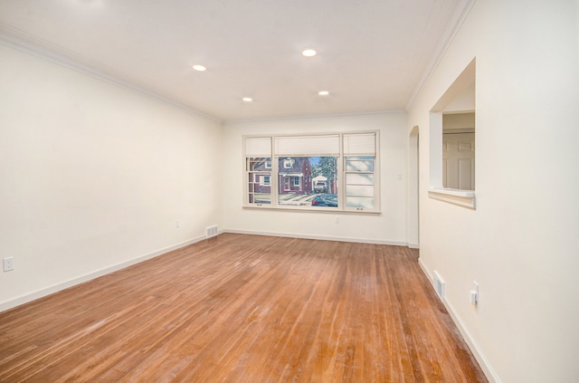 empty room featuring light wood-type flooring and ornamental molding