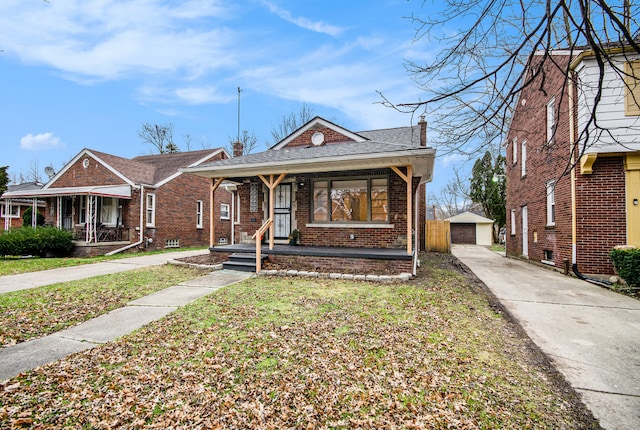 bungalow-style house with a garage, a porch, an outdoor structure, a front lawn, and brick siding