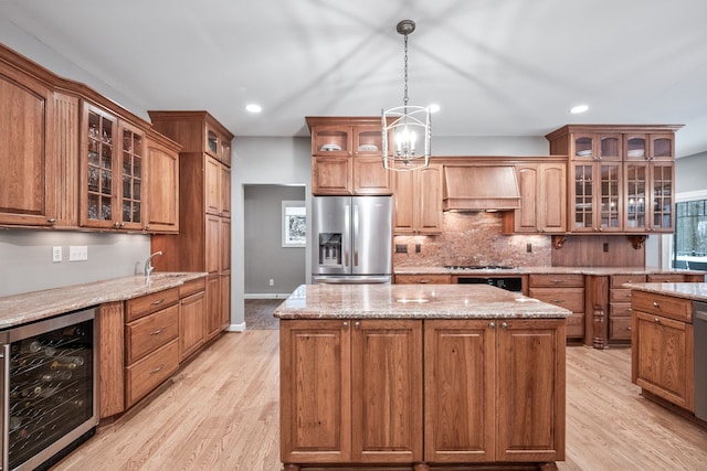 kitchen with wall chimney range hood, beverage cooler, a kitchen island, and appliances with stainless steel finishes