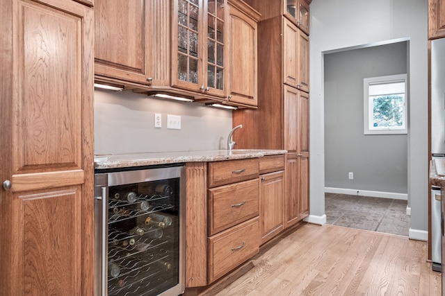 bar with light stone counters, light hardwood / wood-style flooring, and wine cooler