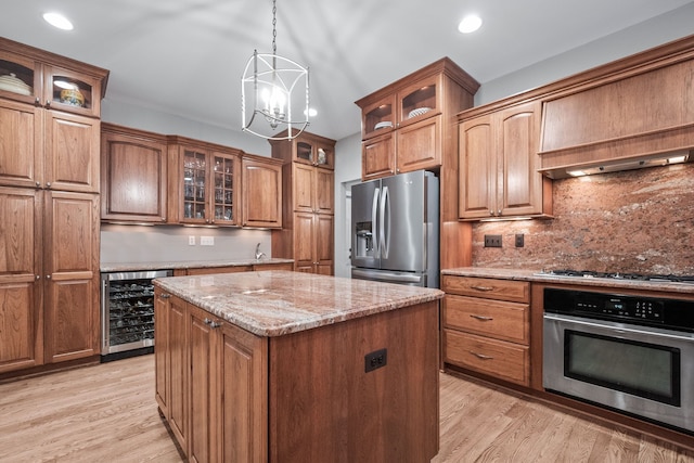 kitchen featuring stainless steel appliances, a notable chandelier, beverage cooler, pendant lighting, and a center island