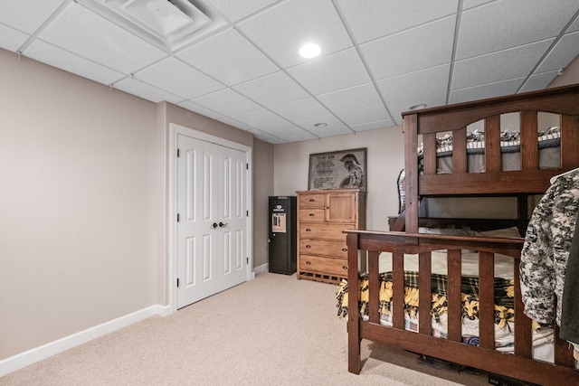 carpeted bedroom featuring a closet and a paneled ceiling