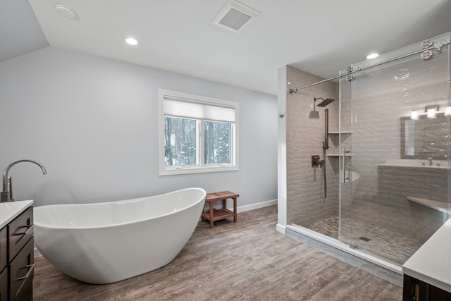 bathroom with wood-type flooring, vaulted ceiling, vanity, and shower with separate bathtub