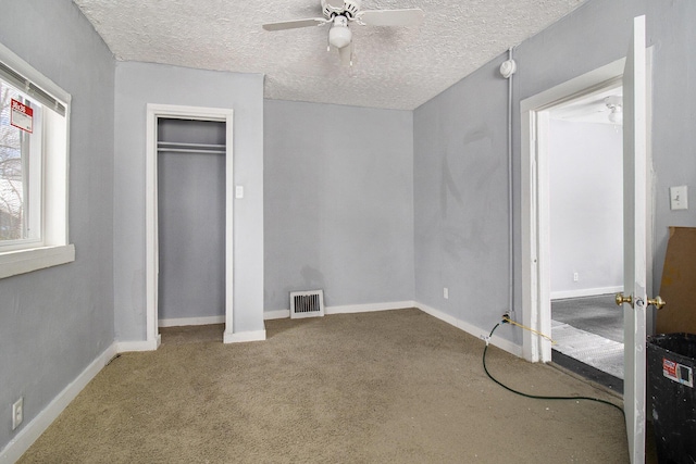 unfurnished bedroom with ceiling fan, carpet, and a textured ceiling