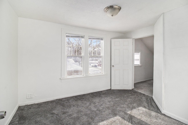 carpeted spare room featuring vaulted ceiling and a textured ceiling