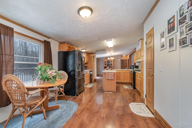 kitchen featuring a textured ceiling, stainless steel appliances, kitchen peninsula, hardwood / wood-style flooring, and crown molding