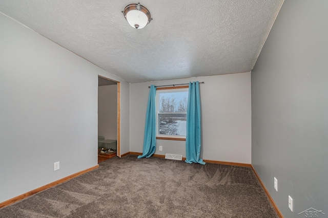 carpeted spare room featuring a textured ceiling and lofted ceiling