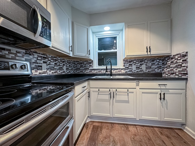 kitchen with hardwood / wood-style floors, appliances with stainless steel finishes, white cabinets, and sink