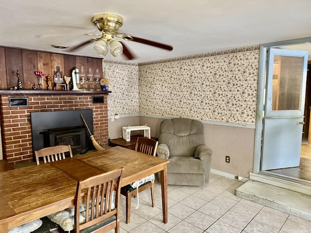 tiled dining room featuring ceiling fan and a wood stove