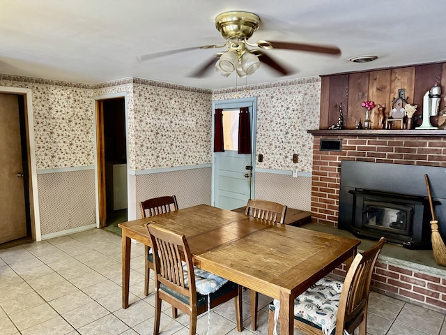 tiled dining space featuring ceiling fan and a wood stove