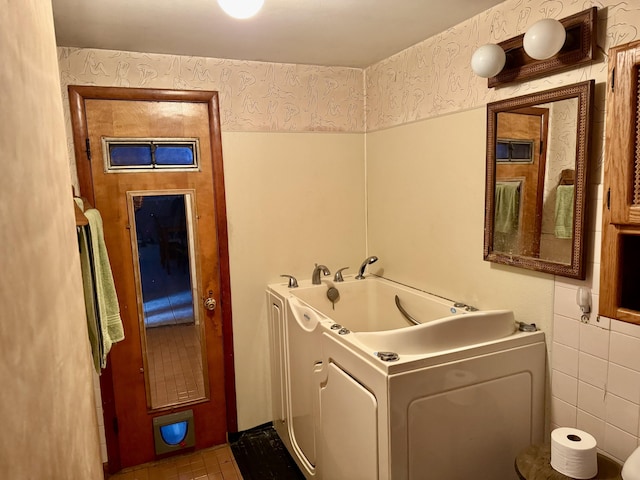 clothes washing area with tile walls and washer / clothes dryer