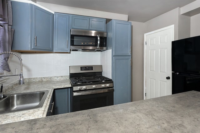 kitchen with sink, appliances with stainless steel finishes, blue cabinetry, and tasteful backsplash