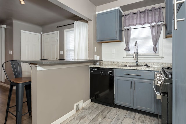 kitchen featuring dishwasher, a breakfast bar, kitchen peninsula, sink, and gas range