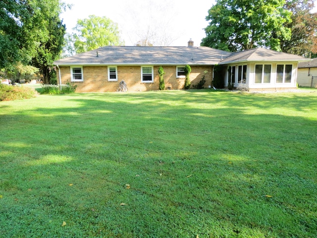 rear view of property featuring a lawn and a sunroom