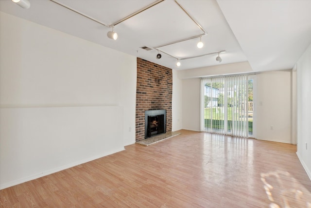 unfurnished living room with a fireplace, track lighting, and light hardwood / wood-style flooring